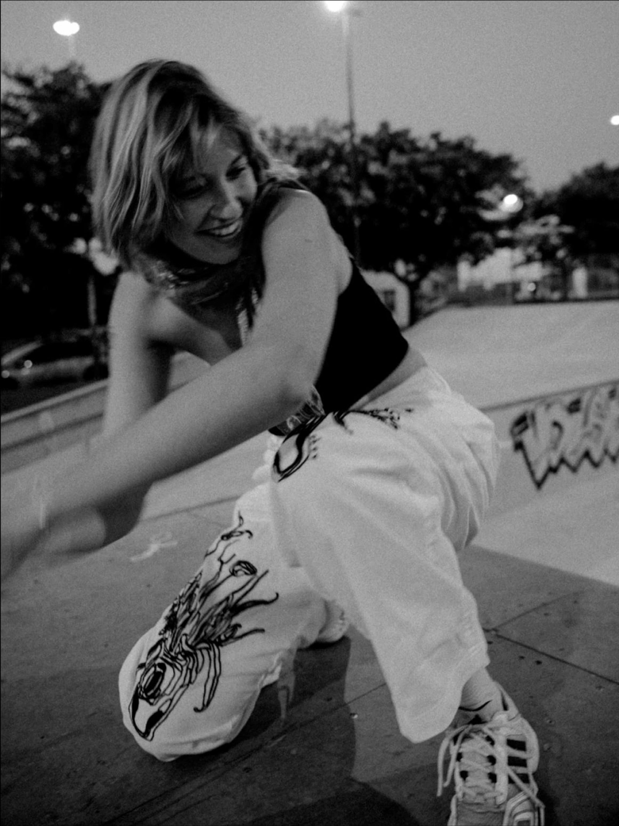 young woman laughing while sitting on a halfpipe in a skate park