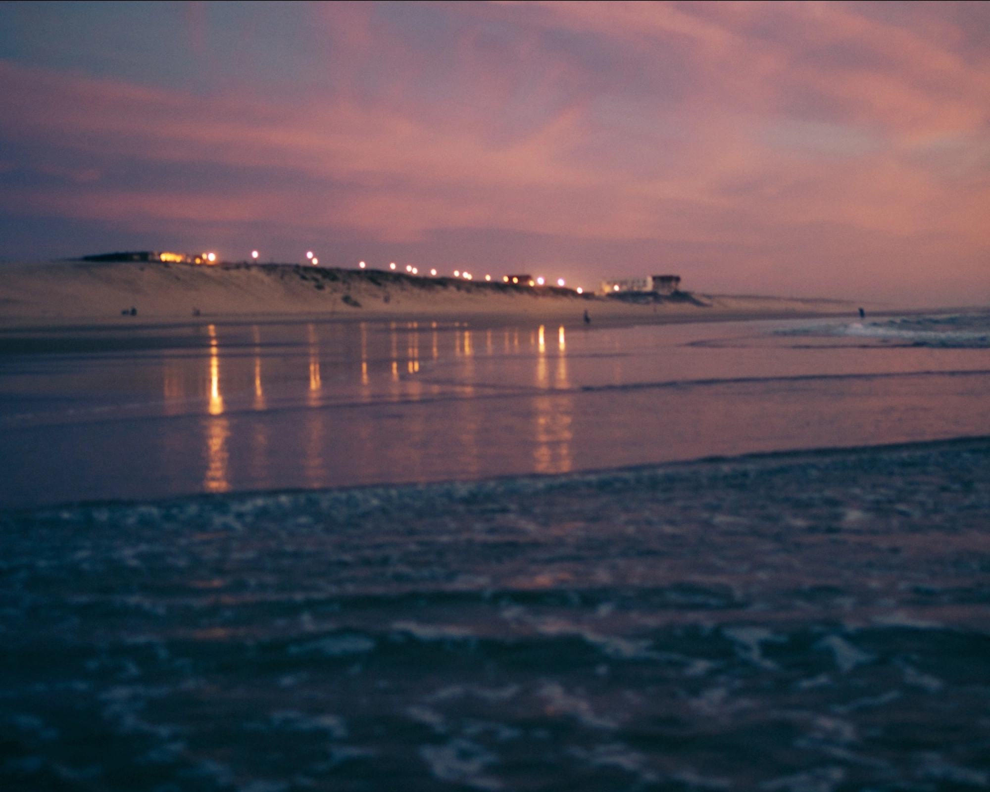 sunset of the atlantic coastline with lights reflecting from the water